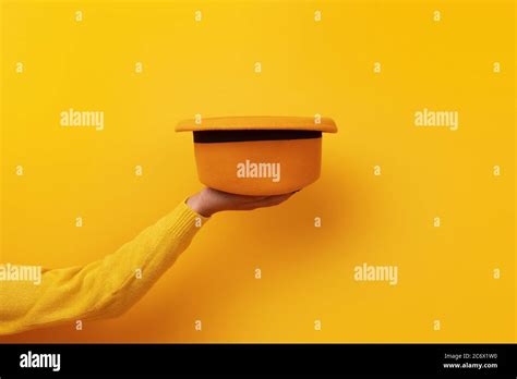 Fashionable Yellow Felt Hat On Hand Over Yellow Background Stock Photo