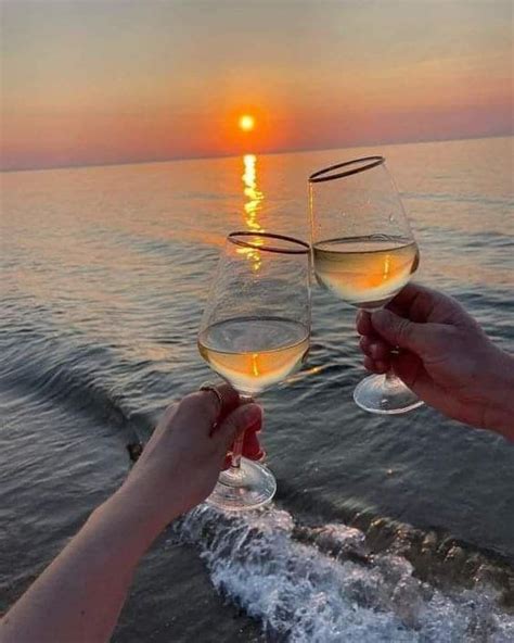 Two People Toasting With White Wine On The Beach At Sunset Or Sunrise