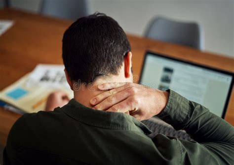 Man Suffering From Neck Pain While Working On Laptop Stock Photo