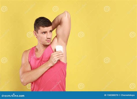 Young Man Applying Deodorant To Armpit Space For Text Stock Photo