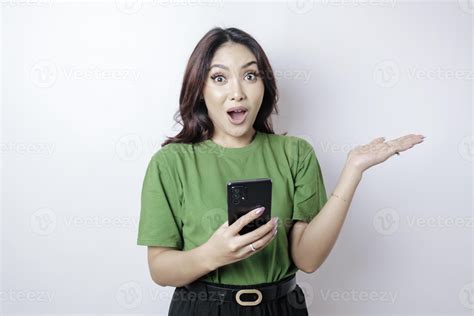 Shocked Asian Woman Wearing Green T Shirt Pointing At The Copy Space Beside Her Holding Her