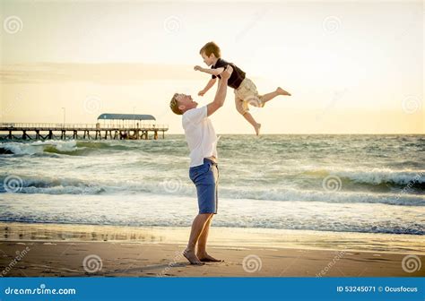 Young Happy Father Holding Up In His Arms Little Son Putting Him Up At