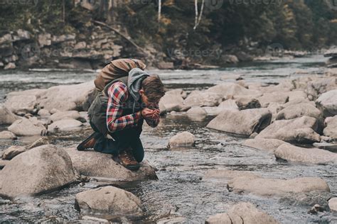 Handsome Young Modern Man Drinking Water From The River While Hiking In