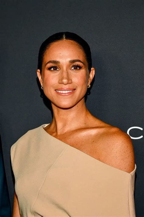 A Woman In A Tan Dress Smiling At The Camera With Her Arm Around Her