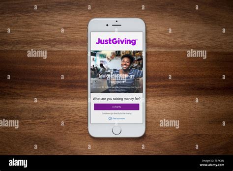 An Iphone Showing The Justgiving Website Rests On A Plain Wooden Table