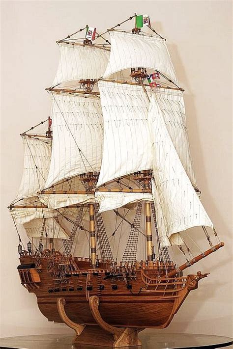 A Wooden Model Ship On Display In A Glass Case With White Sails And Two