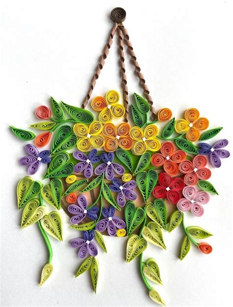 A Multicolored Paper Flower Hanging From A String On A White Wall With