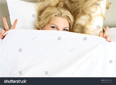 Happy Beautiful Girl Covering With A White Blanket In Her Bed At Home