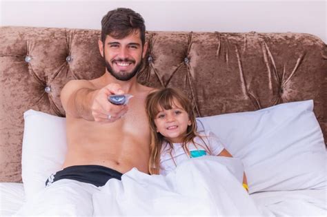 Pai E Filha No Quarto Sentado Na Cama Assistindo Tv Foto Premium