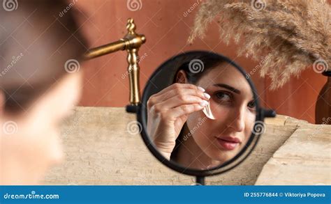 Mirror Reflection Of Woman Applying Under Eye Patch At Dressing Table