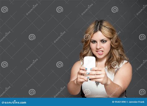 Teenage Girl Biting Into Her Lips Is Looking At Her Smart Phone Stock