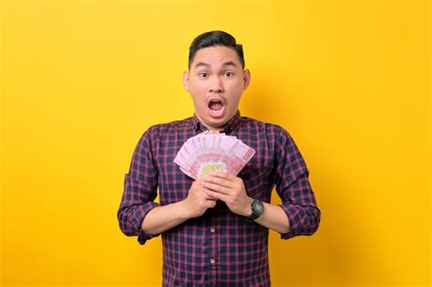 Premium Photo Surprised Young Asian Man Holding Money Banknotes And