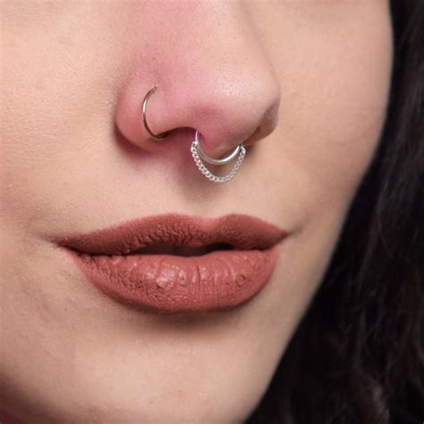 A Close Up Of A Woman With A Nose Ring On Her Nose And An Ear Piercing