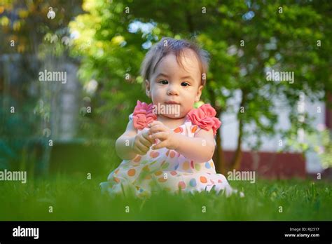 Portrait Of Baby Girl Sitting On Green Grass Background Stock Photo Alamy