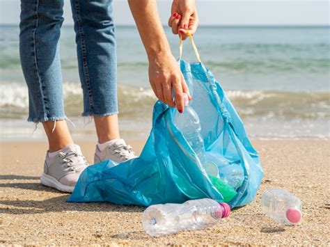 Mujer recogiendo botellas de plástico reciclables en la basura Foto