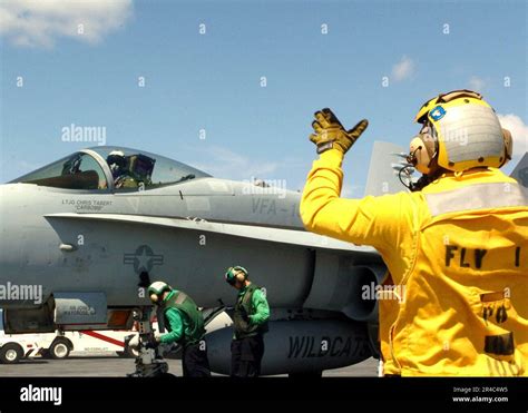 Us Navy A Sailor Signals To The Pilot Of An F A C Hornet Assigned To