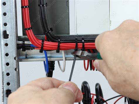 Installation of a cable tie on an insulated mounting wire in an electrical panel. Stock Photo ...