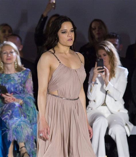 A Woman Is Walking Down The Runway In A Dress