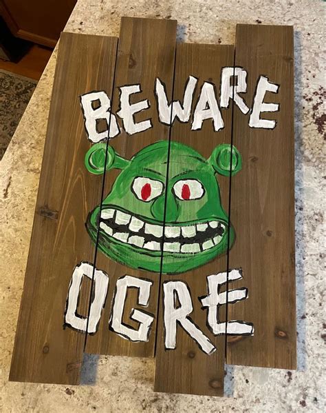 A Wooden Sign That Says Beware Of The Ogre With An Evil Green Face