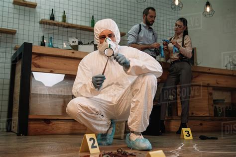 Forensic Investigator Examining Evidence With Magnifying Glass At Crime