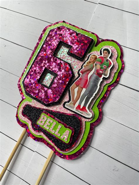 A Pink And Green Cake Topper With The Number Five On It S Side