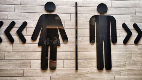 Male And Female Restroom Symbols On A Wooden Wall With Directional