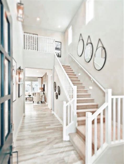 A Large White Staircase Leading Up To A Living Room With Two Clocks On