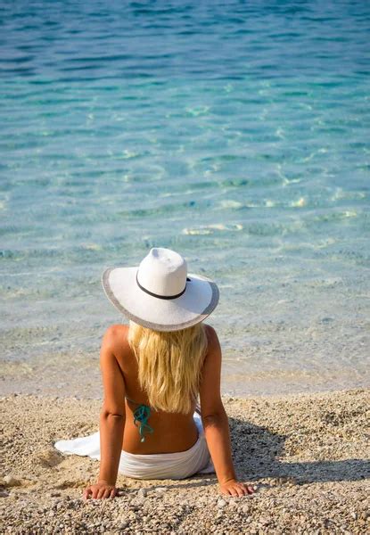 Blonde In Bikini Sitting On A Rock At Beach Stock Photo