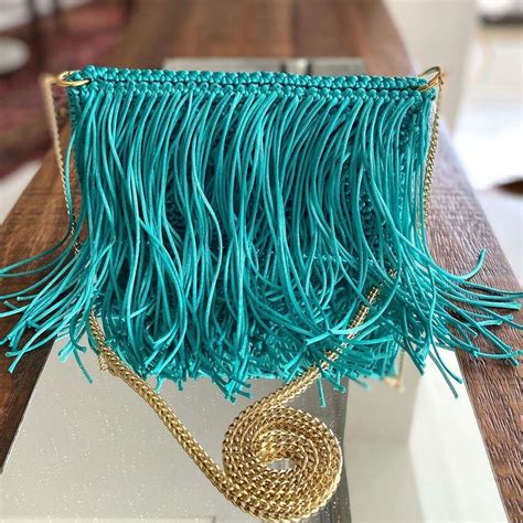 A Blue Purse With Fringes On It Sitting On A Wooden Table Next To A Mirror