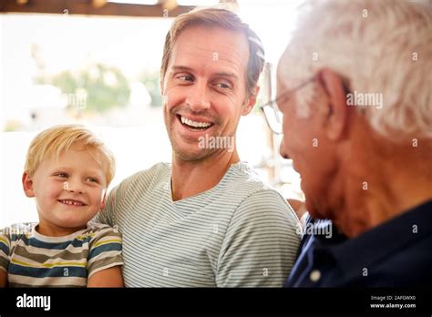 Father With Adult Son And Grandson Relaxing On Sofa And Talking At Home