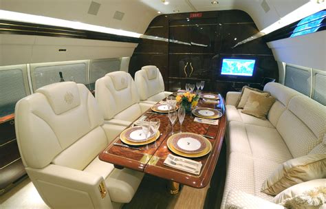 a dining area in an airplane with white leather seats and wooden table set for four