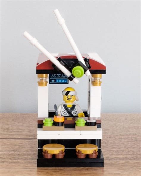 a lego man is sitting in front of a machine with three cups on the table