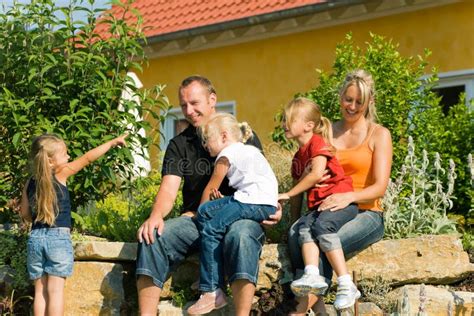 Famille S Asseyant Devant Leur Maison Photo Stock Image Du Bleu