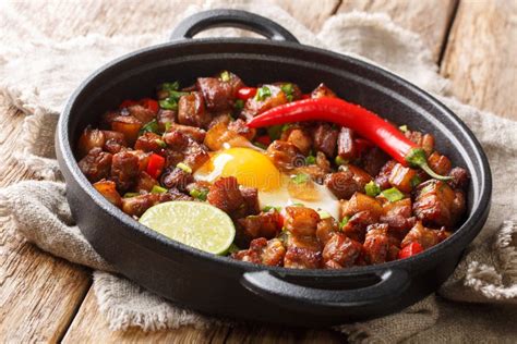 Sizzling Spicy Pork Sisig With Egg Ang Lime Close Up In A Pan