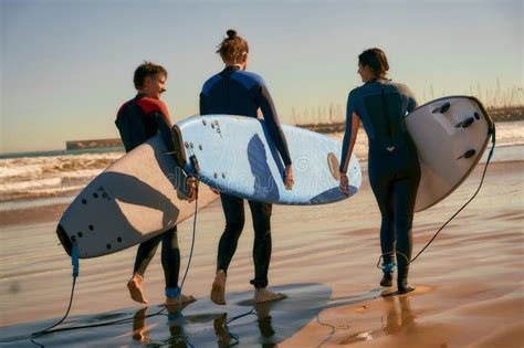 Group Of Friends With Surfboards Entering Towards Ocean For Surfing On