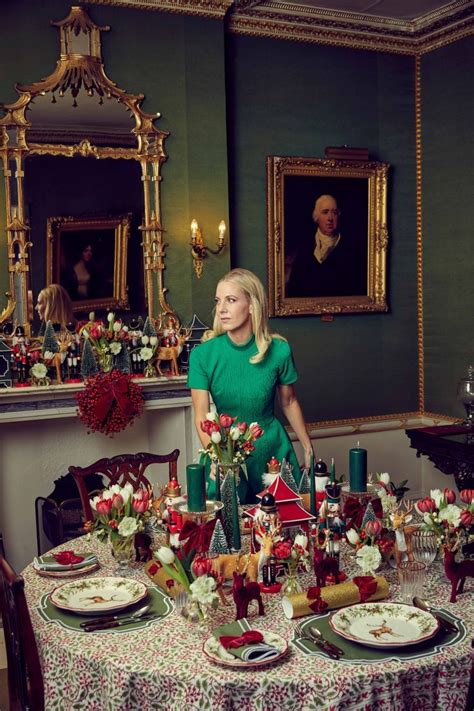 A Woman Standing In Front Of A Table With Plates And Flowers On It