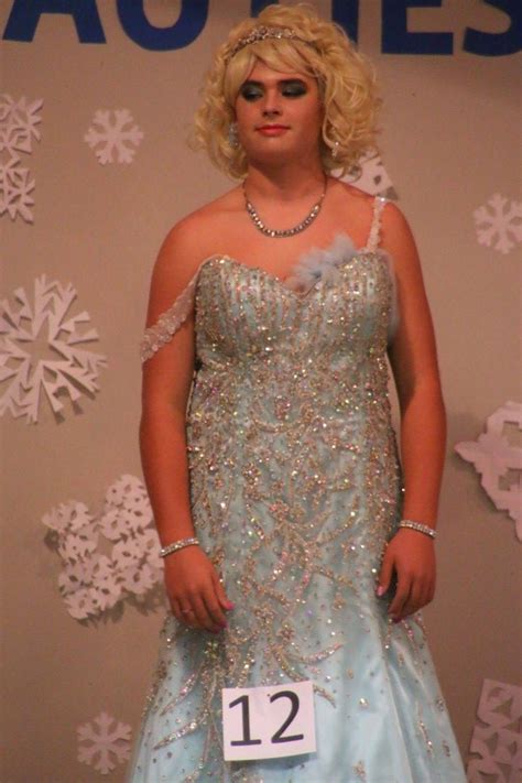 A Woman In A Blue Dress Standing Next To A Snowflake Wall With The