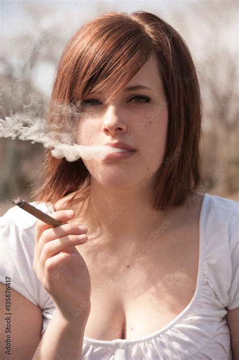 Cute Brunette Exhales Smoke Out Of Her Mouth Outside Smoking A Cigar