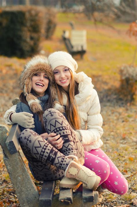 Two Beautiful Girls Sitting On The Bench Outdoor On Sunny Autumn Stock