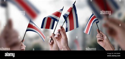 A Group Of People Holding Small Flags Of The Costa Rica In Their Hands