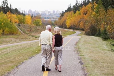 Mature Married Couple Walking Together In Park During Fall Season