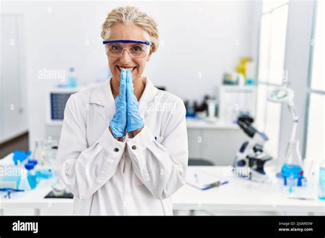 Middle Age Blonde Woman Working At Scientist Laboratory Praying With