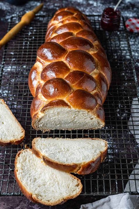 A Loaf Of Bread Sitting On Top Of A Cooling Rack Next To Slices Of Bread