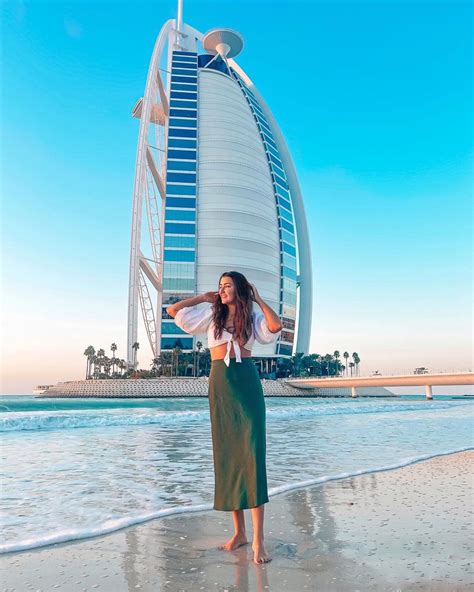 A Woman Standing On The Beach In Front Of Burj Al Araba Hotel