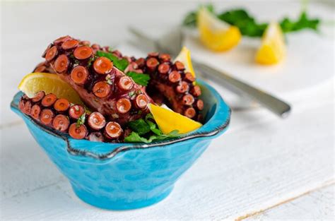 Pulpo hervido con limón y perejil en un recipiente azul Foto Premium