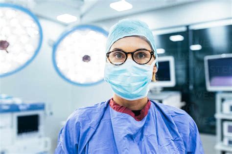 Close Up Portrait Of Female Surgeon Wearing Surgical Mask And Scrubs In