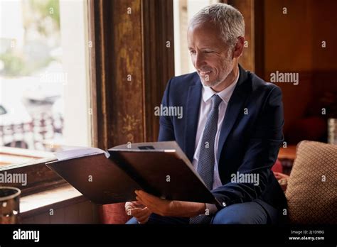 Whats On The Menu For Today Shot Of A Well Dressed Mature Man Reading