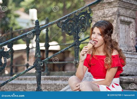 Attractive Brunette Girl With Red Blouse Eating Ice Cream In Outdoor