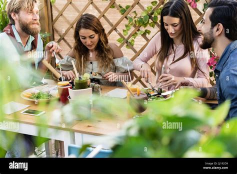 Young People Eating Brunch And Drinking Smoothies At Healthy Food Bar