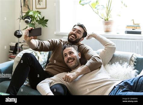 Happy Gay Couple Taking Selfie Through Mobile Phone While Relaxing On